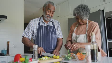 Glückliches-Afroamerikanisches-Seniorenpaar,-Das-Zusammen-Kocht-Und-Redet