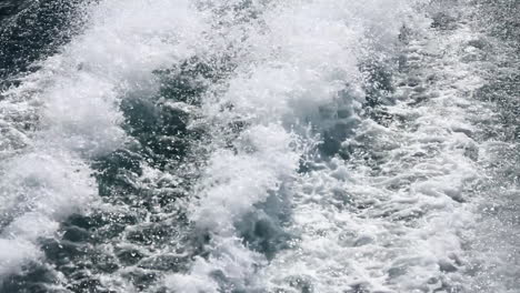 wake waves form alongside boat on ocean