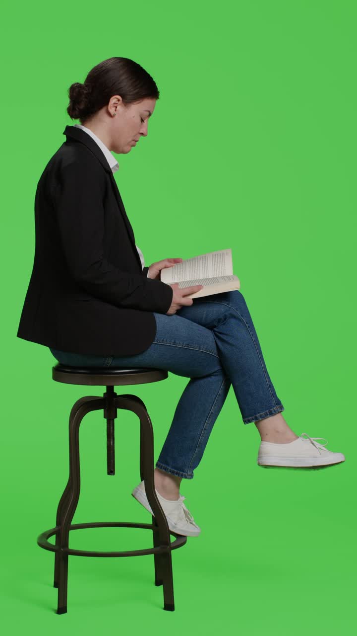 Video verticale: Ritratto di donna d'affari concentrata che legge un libro seduta su una sedia