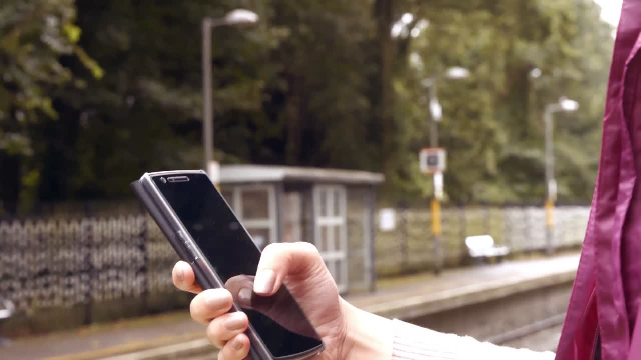 mujer de negocios usando el teléfono en la plataforma del tren