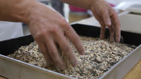 el panadero mezcla la mezcla de barras de cereal seco con las manos en la bandeja de horneado