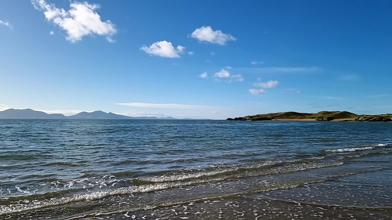 천상의 흐릿한 해가 뜨는 아래에서 느리게 움직이는 조류와 물결, 뉴보로 섬의 스카이 라인.