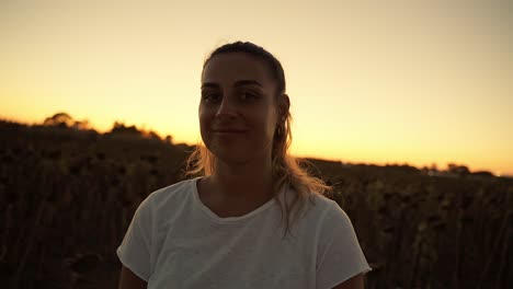 first wide shot of a woman in an orange sunset looking at the camera and smiling