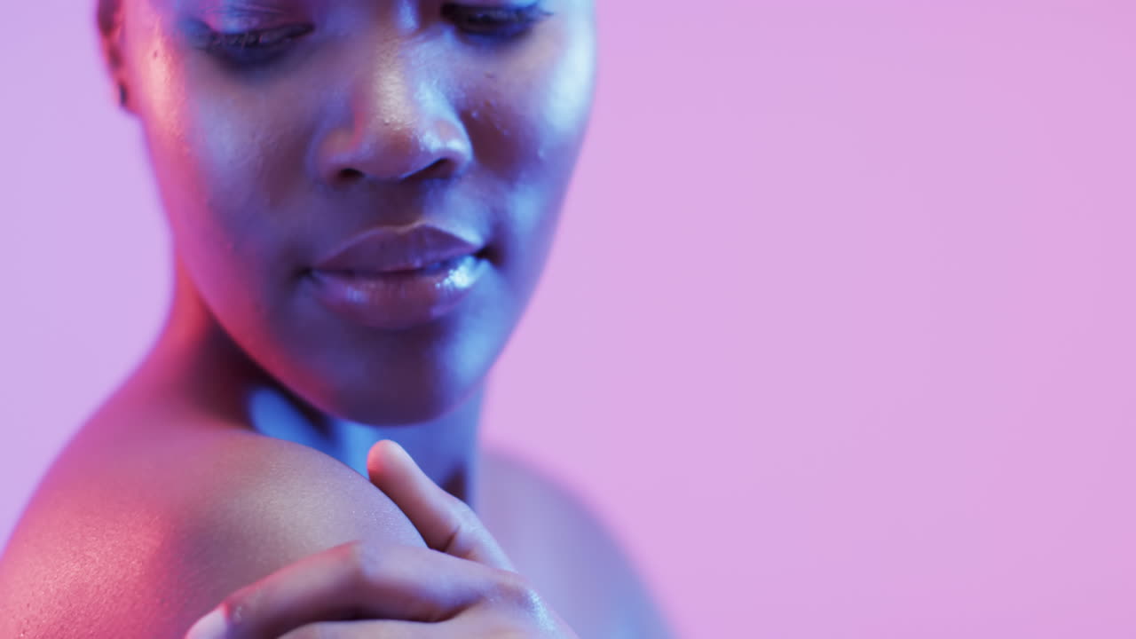 mujer afroamericana con cabello oscuro corto en luz azul y rosa con espacio de copia, cámara lenta