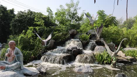 pájaros volando alrededor de una estatua de buda serena por la cascada