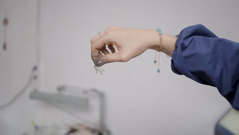woman holding metal jewelry piece in a workshop setting
