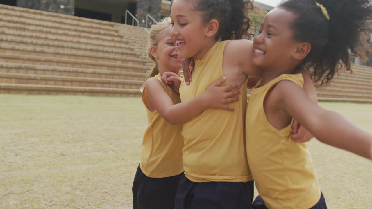 Vídeo das pernas de meninas diversas se abraçando após um jogo de futebol em frente à escola