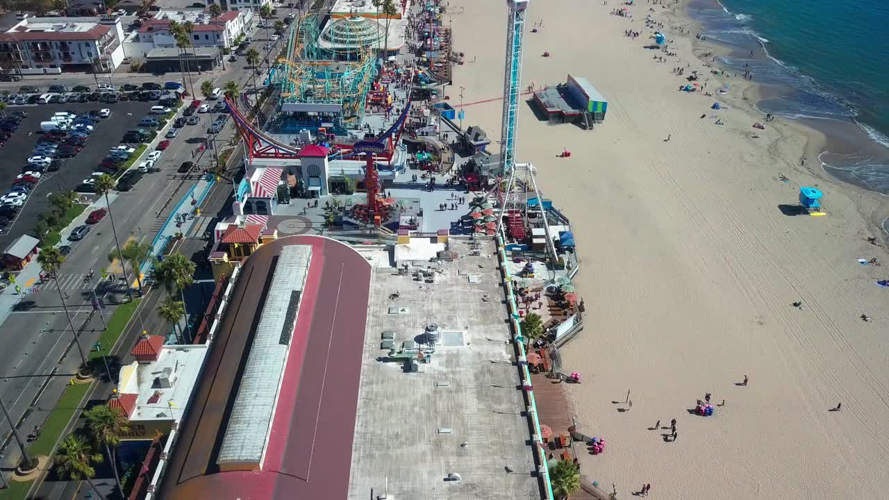 Low aerial glide over beach boardwalk amusement park. 4K
