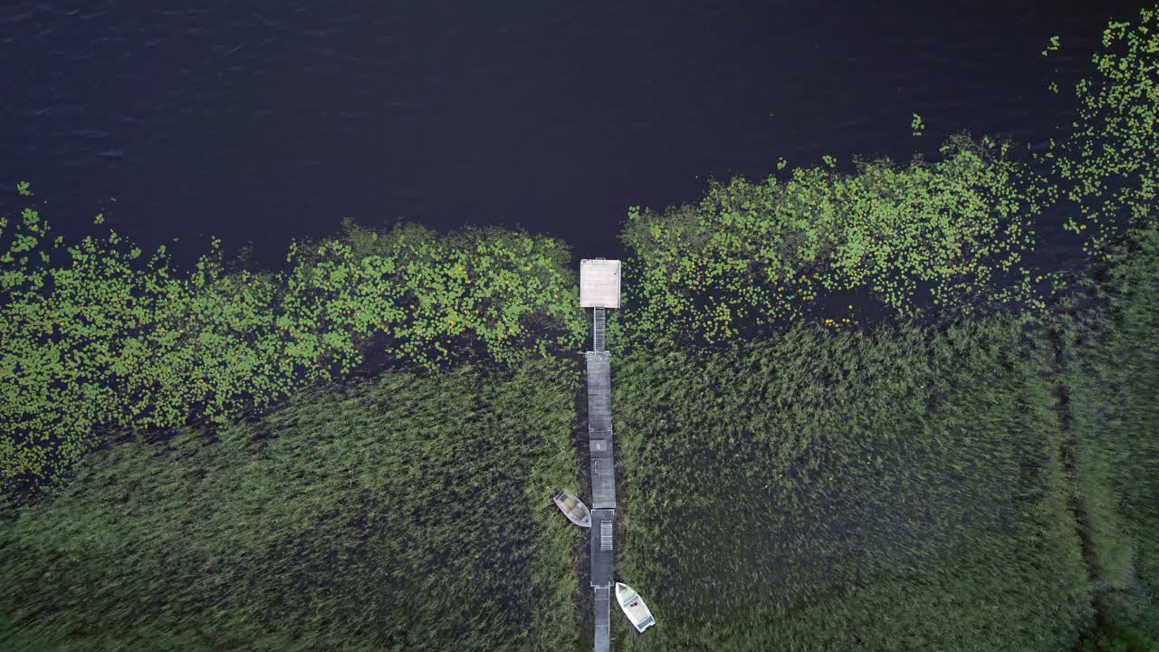 두 척의 보트가 있는 작은 자란 목재 부두, 스웨덴, 하향식 정적 드론 샷