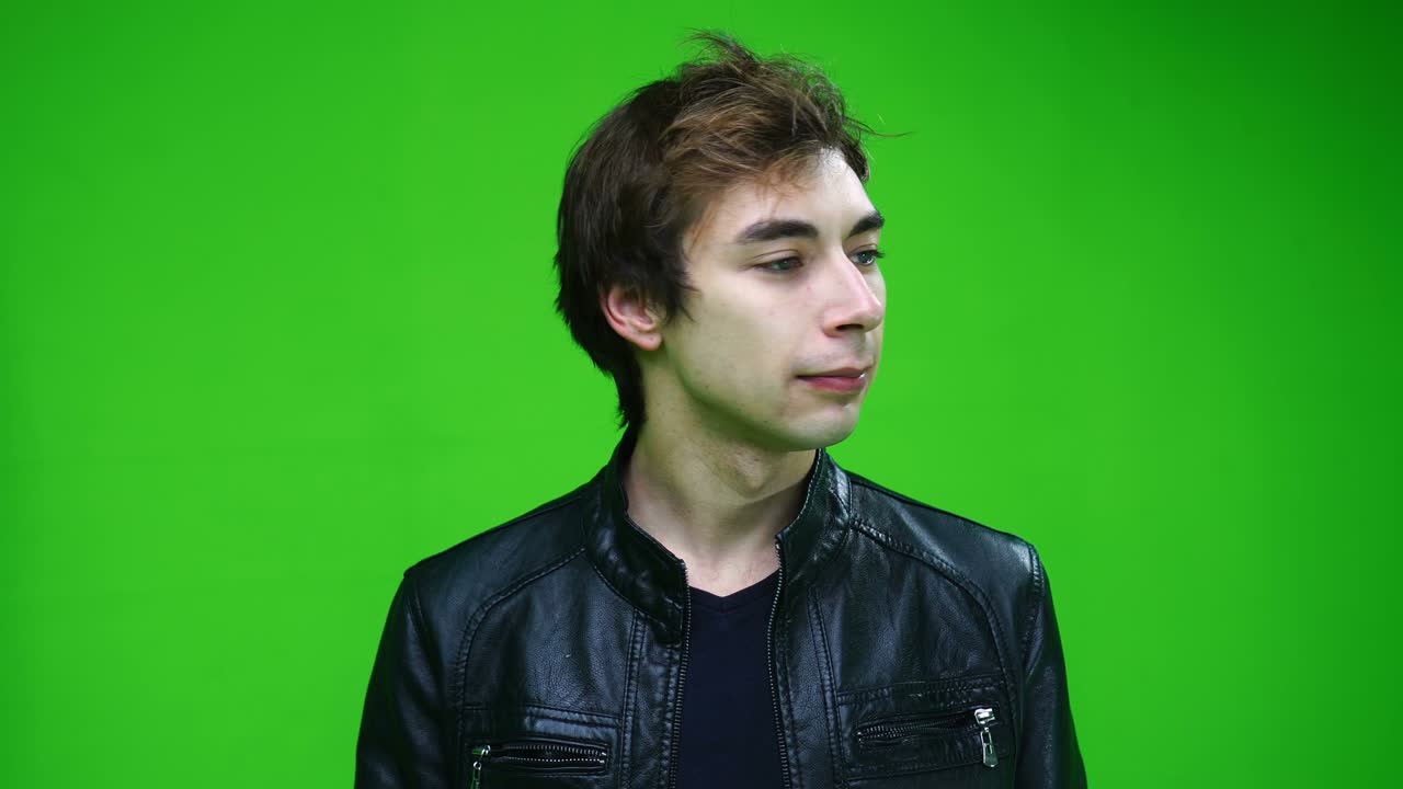 un hombre blanco con chaqueta de cuero asenta con la cabeza y dice que no sobre un fondo verde.