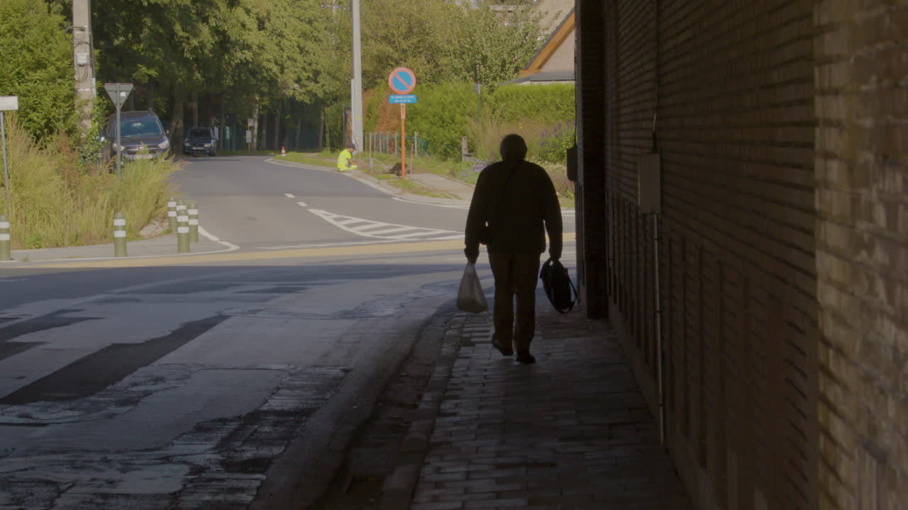 슬로우 모션으로 터널을 걷는 비닐 식료품 가방을 든 노인