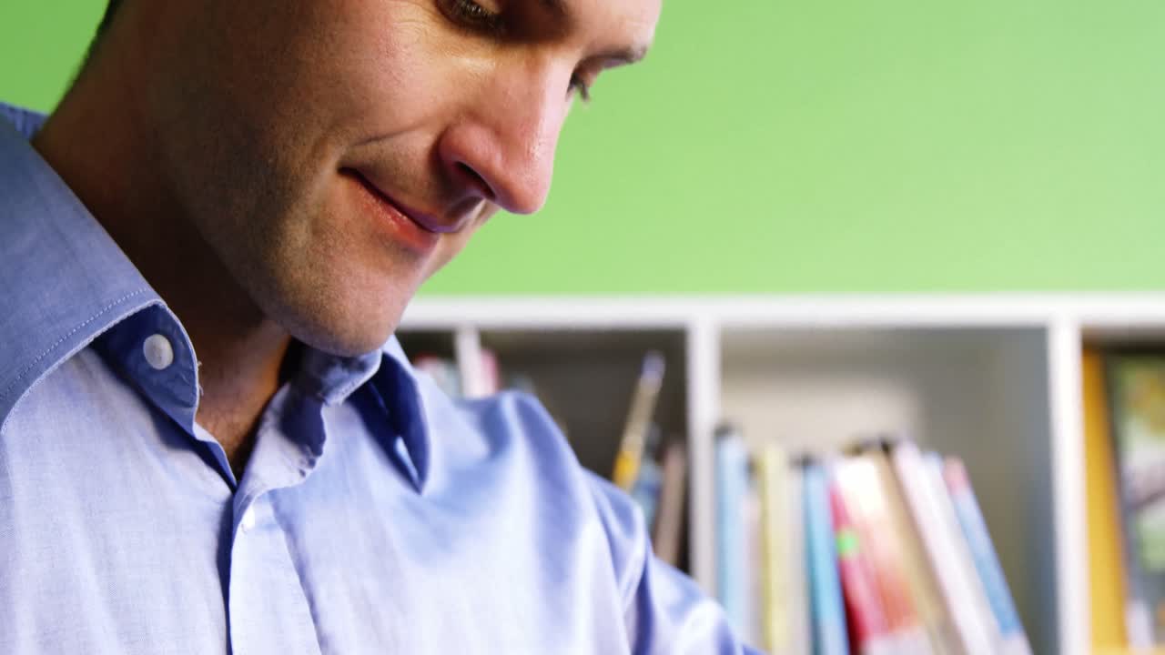 maestro sonriente ajustando un reloj inteligente en la biblioteca de la escuela