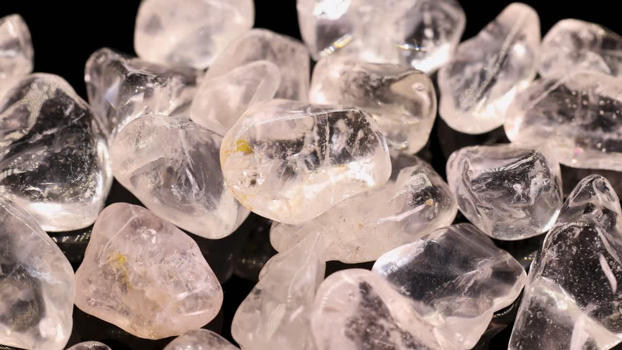 Clear quartz stones arranged on a black background, illuminated by soft lighting, creating a reflective and serene atmosphere