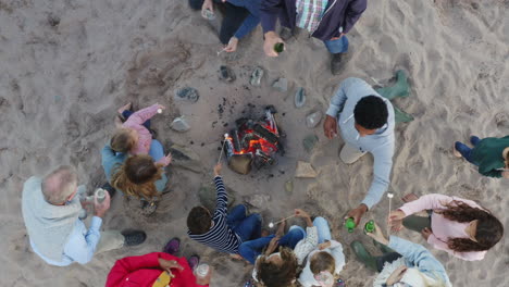 Drohnenaufnahme-Einer-Familie-Aus-Mehreren-Generationen,-Die-Im-Winterlichen-Strandurlaub-Marshmallows-Am-Feuer-Toastet