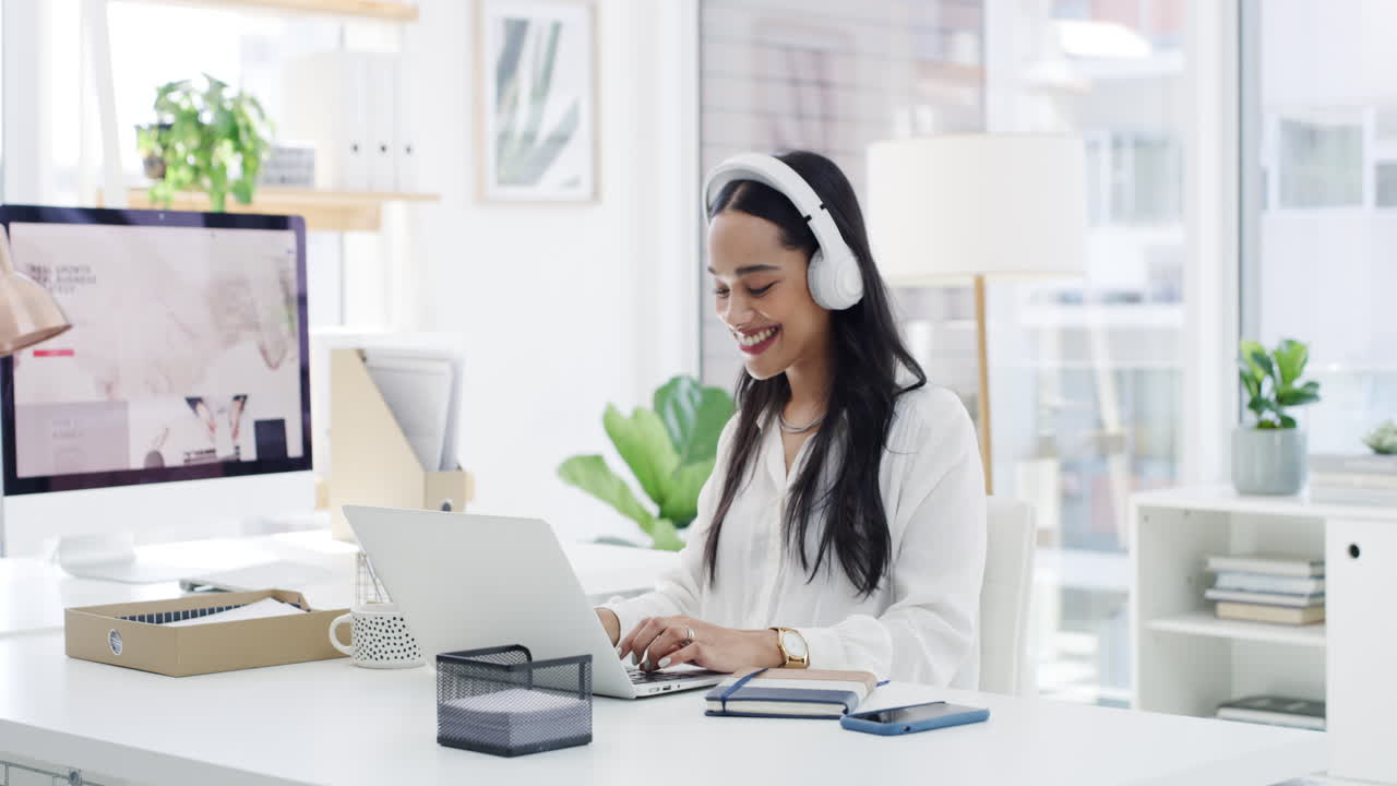 Mujer disfrutando de la música mientras trabaja en su portátil en una oficina moderna