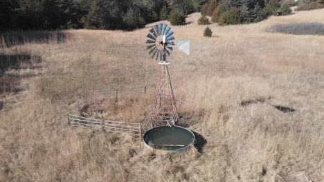 drone shot as it circles around a windmill shifting in the wind near the coniferous forest in nebraska on a sunny day