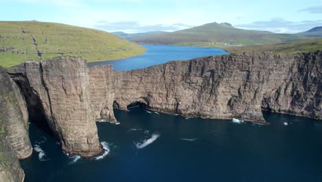 aerial pull back shot reveals the lake above the ocean in faroe islands