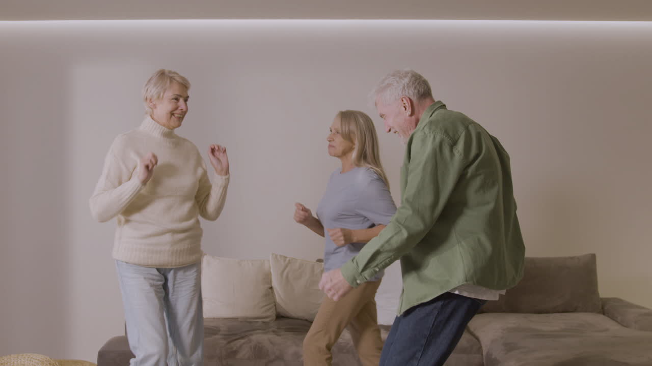 Tre anziani amici felici che ballano insieme a casa