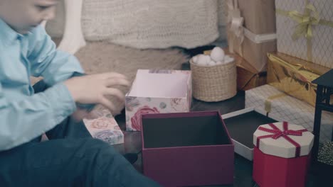 un niño pequeño abre una caja de regalo de navidad y encuentra un teléfono inteligente.