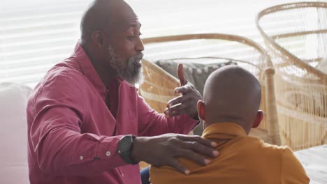 Video-Eines-Nervösen-Afroamerikanischen-Vaters,-Der-Mit-Seinem-Sohn-Auf-Dem-Sofa-Spricht