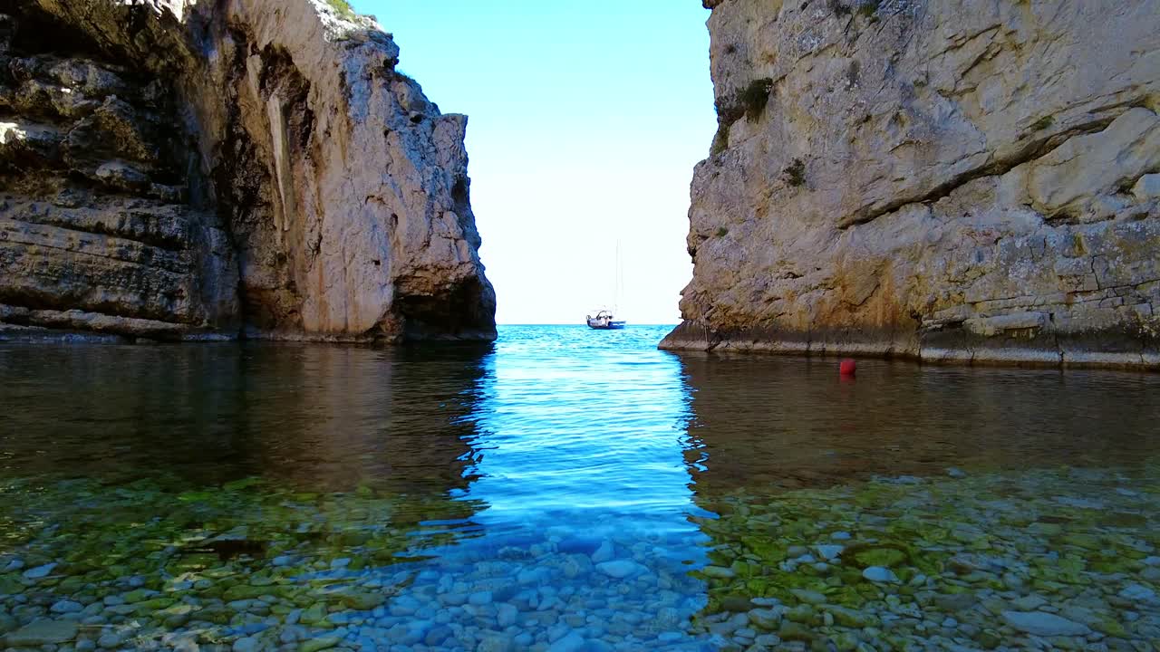 Pebble beach with clear turquoise sea. Panning shot of the Stiniva bay beach, wonder of geology on Vis island, Dalmatia, Croatia.  Amazing Travel destination with a clear turquoise sea and high cliffs