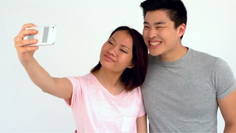 Asian-couple-grimacing-taking-selfie