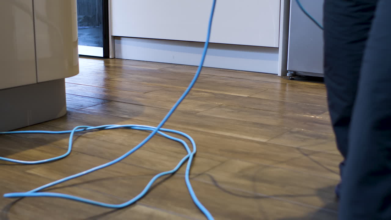 Man Steam Cleaning Wooden Floor In Kitchen