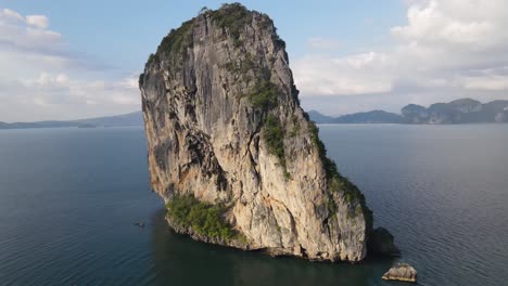 beautiful partly vegetated sheer cliffs of a lone rock called ho ma tang ming in thailand on a sunny day