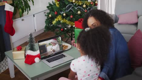 African-american-mother-and-daughter-having-a-videocall-on-laptop-at-home-during-christmas