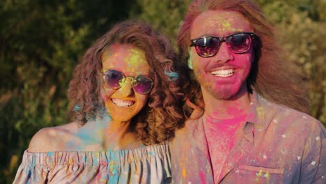 joyful asian woman hugging happy couple covered with paint powder smiling at holi festival