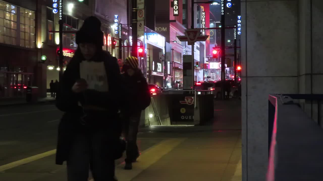 People exiting from TTC Queen Station stairs on Yonge Street and Queen Street during dark night and winter season in Toronto, Ontario, Canada