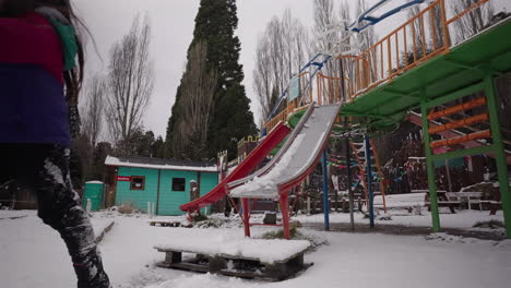 smiling child sliding in snowy playground, joyful winter travel moment in bariloche, argentina