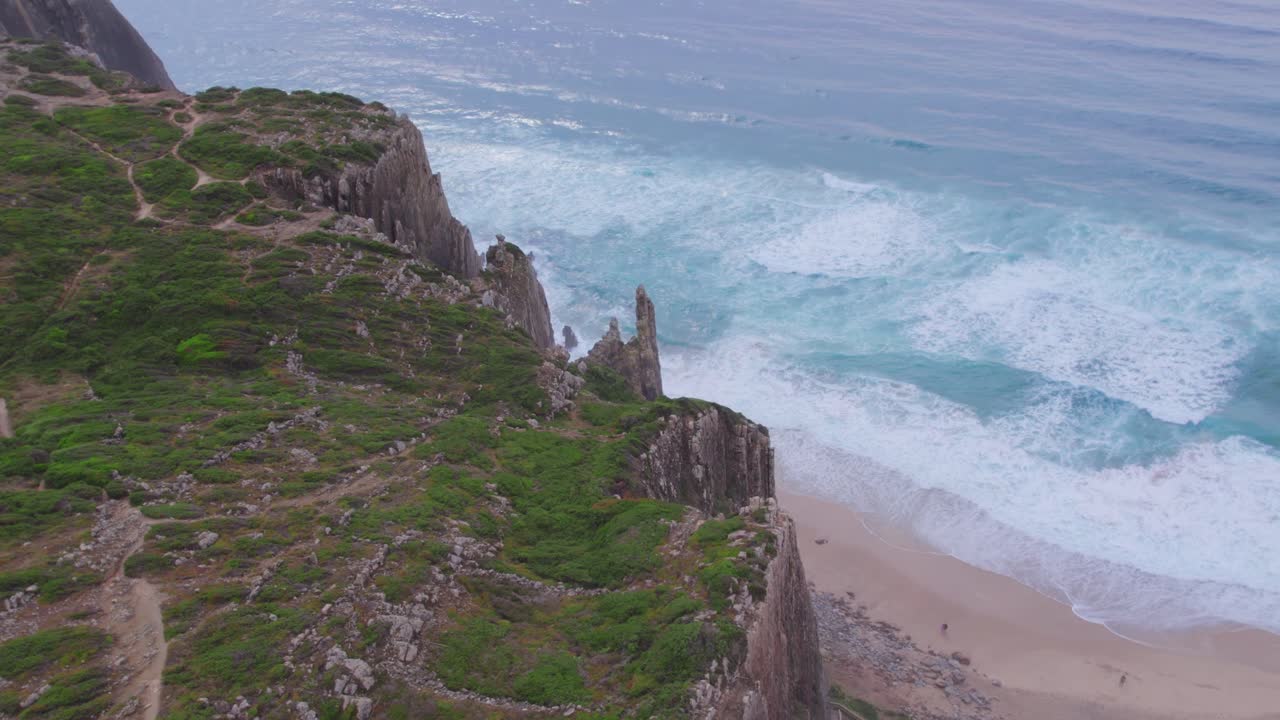 A breathtaking aerial view captures the jagged limestone cliffs of Algarve, Portugal, where lush greenery meets the rolling turquoise surf under soft, diffused light, exuding tranquility