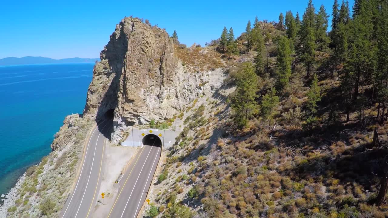 una toma aérea sobre una carretera que atraviesa un túnel a lo largo de la costa del lago tahoe 1