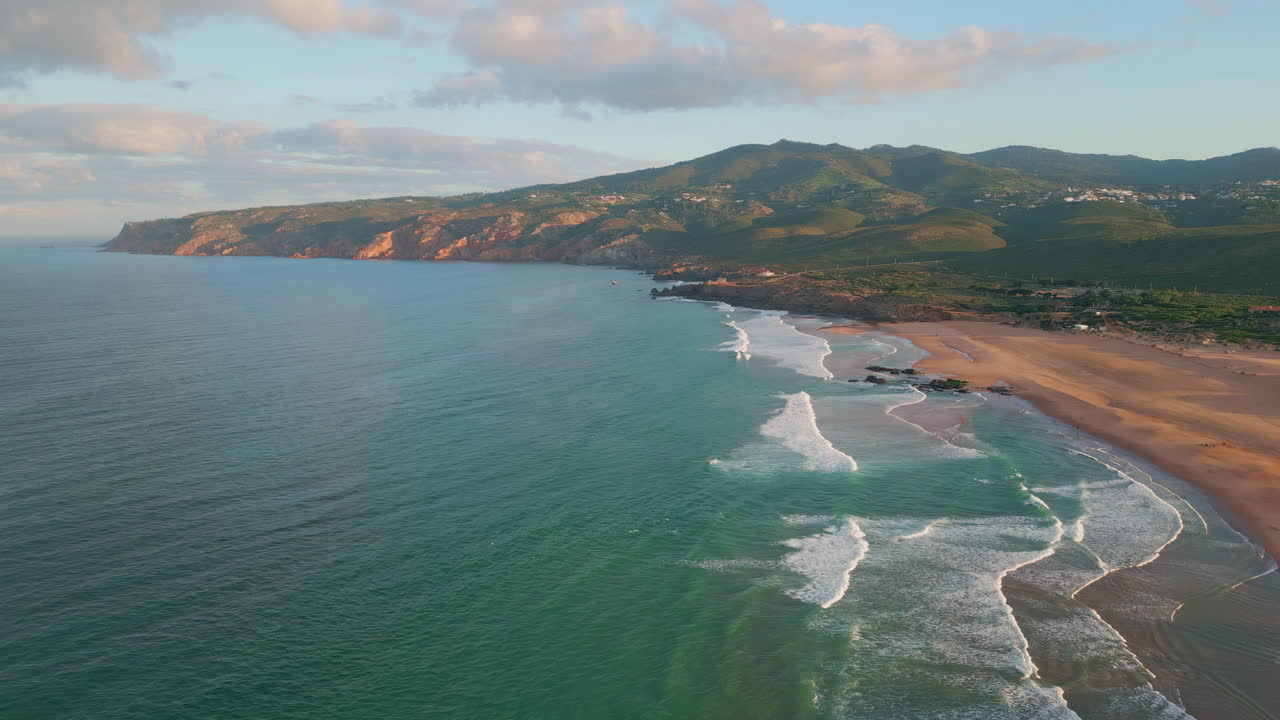Turquoise waves rolling beach in evening light aerial. Sunset embracing shore