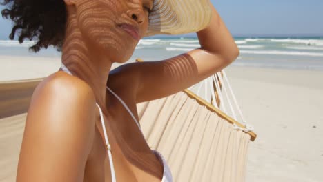 mujer relajándose en una hamaca con sombrero en la playa 4k
