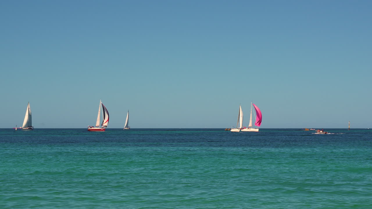 Yacht colorati scivolano sull'oceano blu scintillante in un'affascinante regata sotto cieli sereni. Una vista grandangolare cattura le vele vivaci su acque tranquille, perfetta per temi nautici