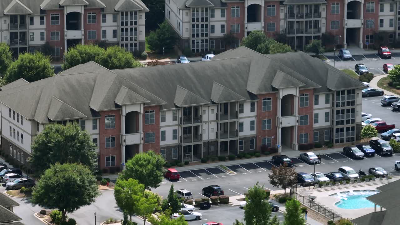 Parking cars in front of new build modern multi family unit apartments in suburb of American town. Sunny day in summer. Private community swimming pool in center. Aerial view