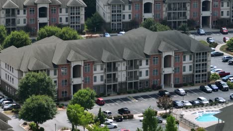 parking cars in front of new build modern multi family unit apartments in suburb of american town. sunny day in summer. private community swimming pool in center. aerial view
