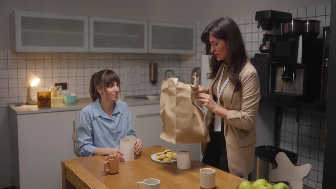 Two women eating lunch in a kitchen