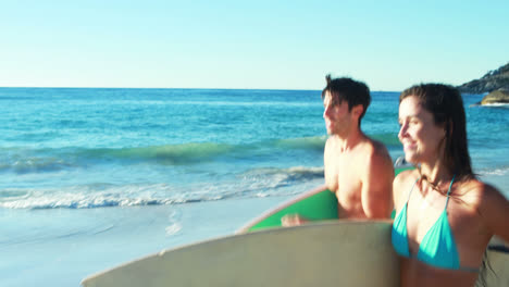 Paar-Läuft-Mit-Surfbrett-Am-Strand