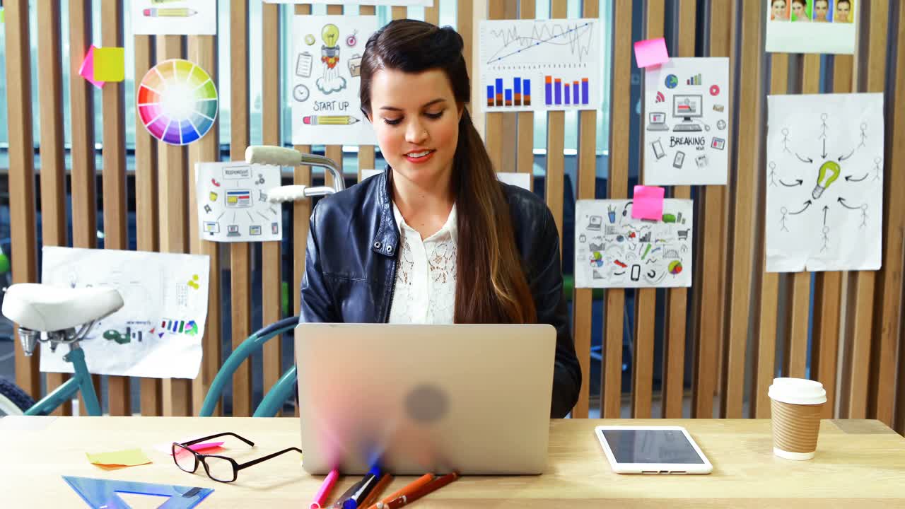 Female executive using laptop and digital tablet at desk