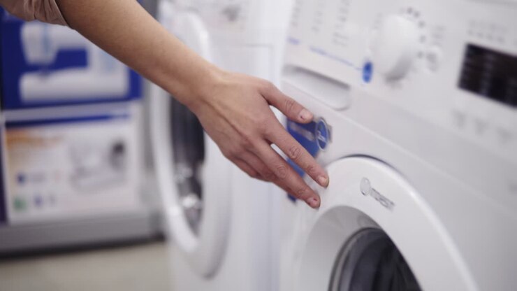 Choosing washing mashine in appliance store. Running hand down the row.