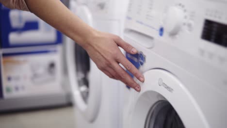 Choosing-washing-mashine-in-appliance-store.-Running-hand-down-the-row.