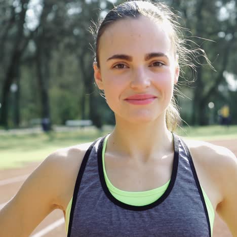 young athletic woman in sportswear resting after jogging workout at track and field stadium