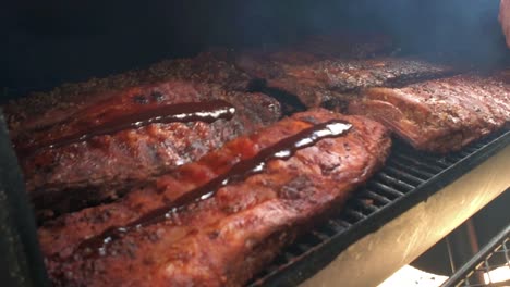 racks of ribs having sauce applied in an off set smoker