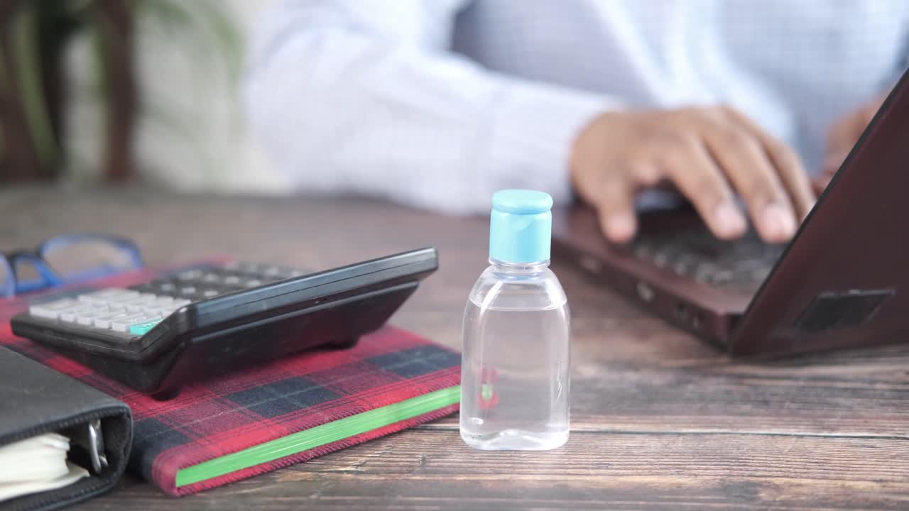 손 소독제를 가지고 책상에서 일하는 사람