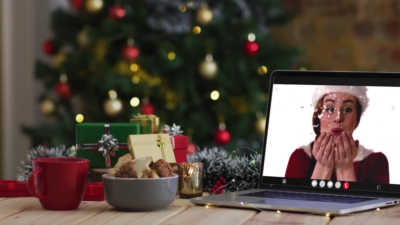 feliz mujer caucásica en disfraz de santa en videollamada en computadora portátil, con decoraciones de navidad y árbol
