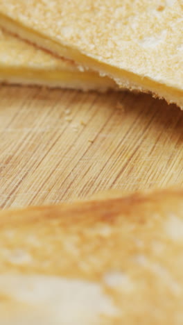 video de rebanadas de sándwiches de pan blanco con queso tostado en el fondo de la tabla de cortar de madera