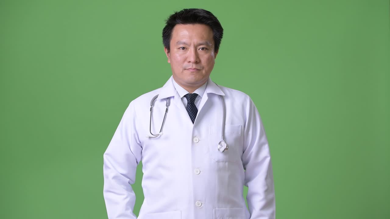 緑の背景に対して成熟した日本人男性医師